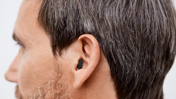 Das Ohr eines Mannes, welcher ein Im-Ohr-Hörgerät trägt